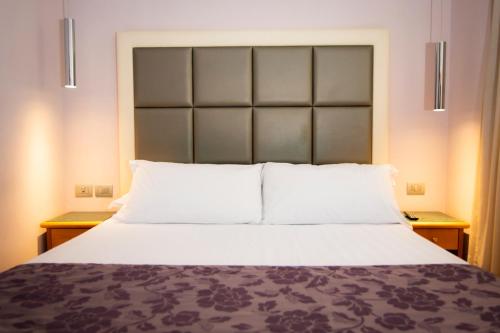a bedroom with a large white bed with two night stands at Hotel Giolli Nazionale in Rome