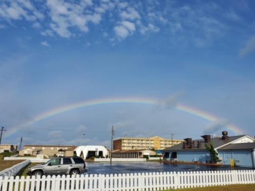 a large rainbow over a parking lot with a car at Outer Banks Motor Lodge in Kill Devil Hills
