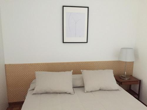 uma cama com duas almofadas e uma fotografia na parede em Tossan House in Vilamoura Downtown em Quarteira
