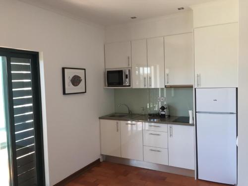 uma cozinha com armários brancos e uma geladeira branca em Tossan House in Vilamoura Downtown em Quarteira