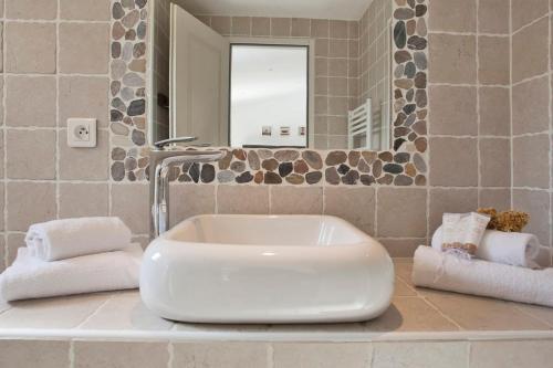 a bathroom with a white sink and a mirror at Amarylis à Calvi location 2 pers avec clim jardin piscine et barbecue in Calvi