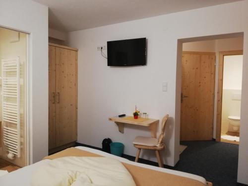 a bedroom with a bed and a table and a tv on the wall at Gästehaus Pürstl-Kocher in Schladming