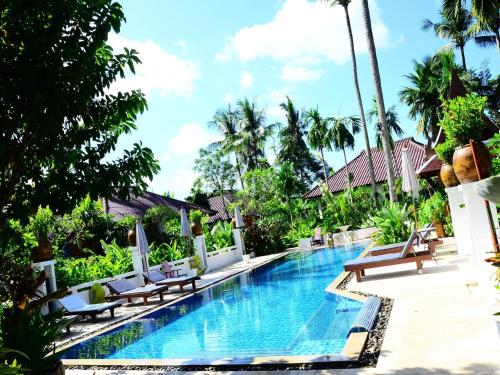 a pool at a resort with chairs and palm trees at Cocoville Phuket - SHA Plus in Chalong 