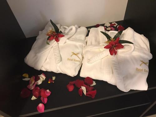 three white towels with red flowers on a bed at Executive Hotel in Feira de Santana