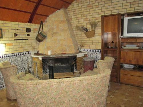 a living room with a fireplace with chairs and a tv at Los Tobares in Gárgoles de Arriba