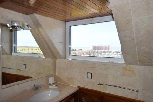 a bathroom with a sink and two windows at Porto Marina Beach Vilamoura in Quarteira
