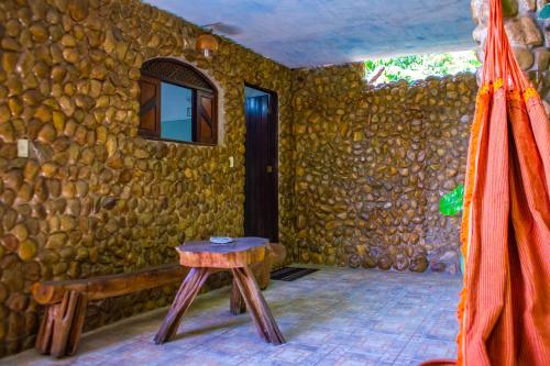a room with a wooden table and a stone wall at Refúgio das Fadas in Pipa