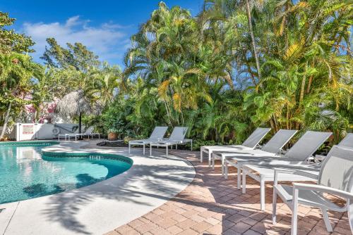 a group of white lounge chairs next to a swimming pool at Sunrise Garden Resort in Anna Maria