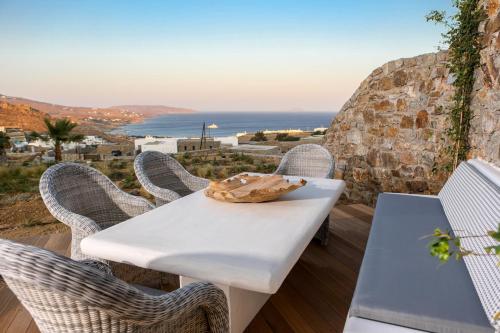 a table and chairs on a balcony with a view of the ocean at Villa Anemoni by Mykonian Kazarte in Kalafatis