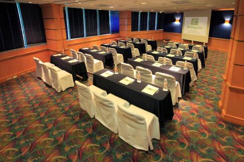 a conference room with tables and white chairs at Holiday Inn Monterrey-Parque Fundidora by IHG in Monterrey