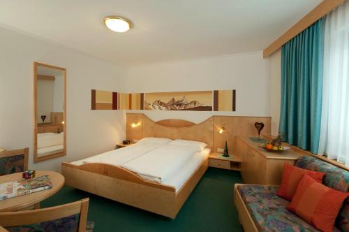 a bedroom with a large bed and a couch at Apart Garni Belfort in Kappl