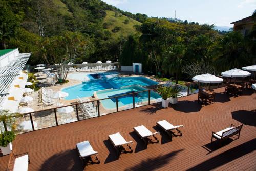 an outdoor deck with a pool and tables and chairs at Plaza Caldas da Imperatriz Resort & Spa in Santo Amaro da Imperatriz