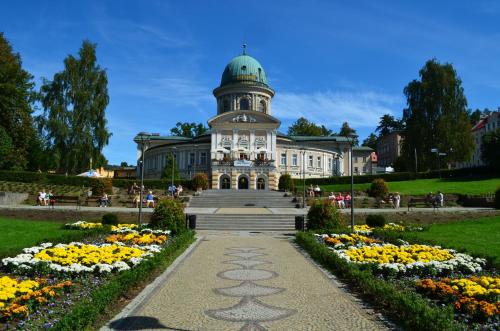 a building with a clock tower in a park with flowers at Zdrój Wojciech in Lądek-Zdrój