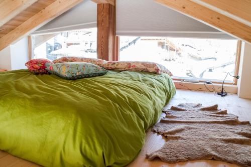 a green bed in a room with a large window at b&bTerre Aromatiche in Chiesa in Valmalenco