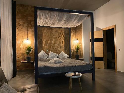 a bedroom with a canopy bed with a brick wall at Kalinova Sloboda Apartment in Ivano-Frankivsʼk