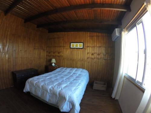 1 dormitorio con 1 cama en una habitación de madera en Serendipia en Maldonado