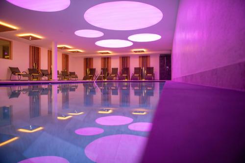 a pool in a hotel with purple lighting and chairs at Hotel Gran Pre in San Vigilio Di Marebbe