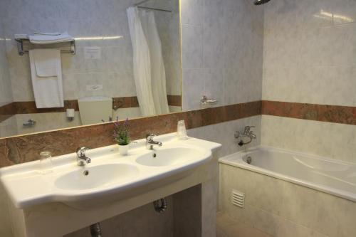 a bathroom with a sink and a tub and a mirror at Hotel Santa Clara in Vidigueira