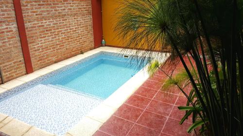 una piscina junto a un edificio de ladrillo con una palmera en Loft Andino I - Comfort moderno a 5' del centro en Salta