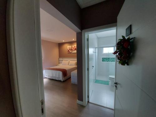 a bedroom with a bed and a door to a bathroom at Hospedagem Jardins de Gramado in Gramado