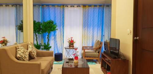 a living room with a couch and a tv at Mactan Newtown - New Modern Condo with Ocean View in Mactan