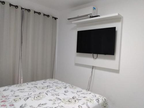 ein Schlafzimmer mit einem TV an einer weißen Wand in der Unterkunft Apartamento para família moderno e prático próximo a belas praias in Cabo Frio