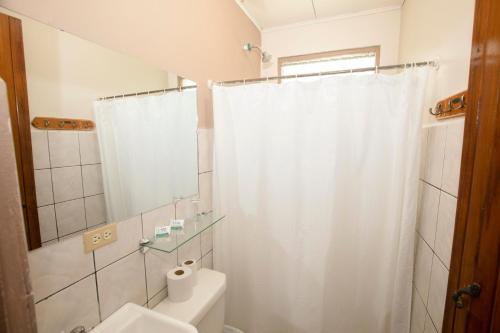 a bathroom with a white shower curtain and a toilet at Hotel Laura's House in Coco