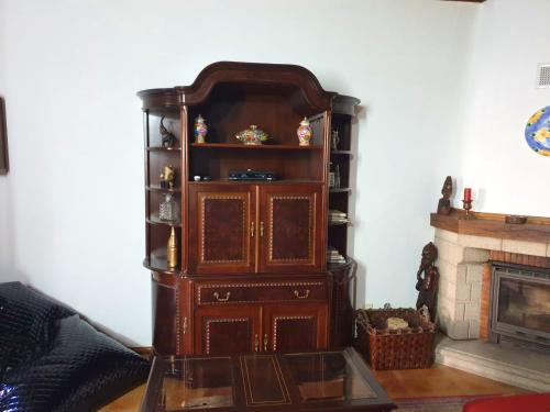 einen großen Holzschrank in einem Wohnzimmer mit Kamin in der Unterkunft Charming House Apendurada in Alpendurada