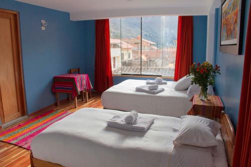 two beds in a room with a window at Tumy house B&B in Ollantaytambo