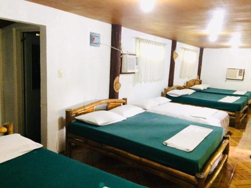 a group of four beds in a room at The Pelicans Resort in Batangas City