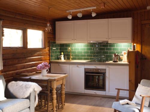 a kitchen with white cabinets and a table with a fireplace at Hillside Log cabin, Ardoch Lodge, Strathyre in Strathyre