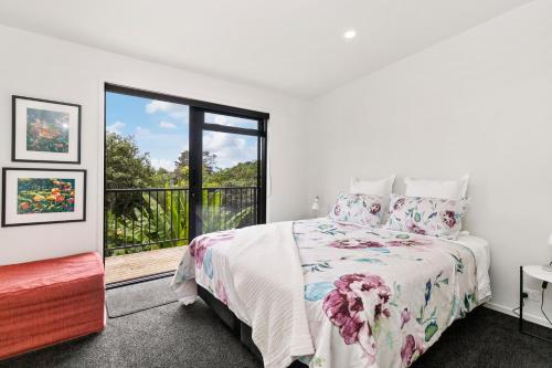 1 dormitorio con cama y ventana grande en Scotts Landing Bach Retreat - Mahurangi East, en Mahurangi