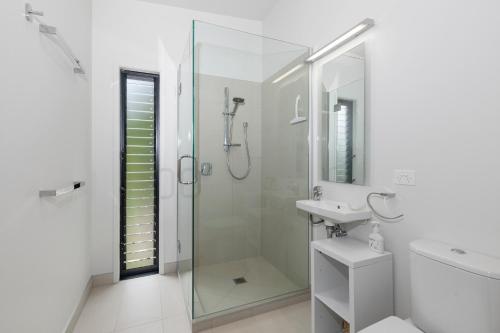 baño blanco con ducha y lavamanos en Scotts Landing Bach Retreat - Mahurangi East, en Mahurangi
