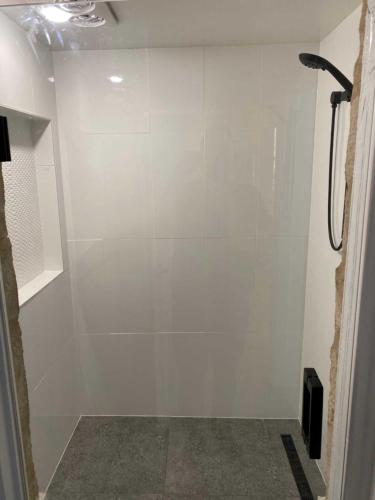 a bathroom with a shower with a white wall at Adelaide Brownhill Creek Tourist Park in Adelaide