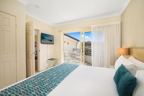 a hotel room with a bed and a balcony at Terrigal Sails Serviced Apartments in Terrigal