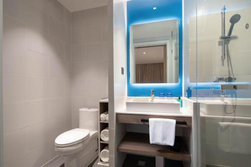 a bathroom with a sink and a toilet and a mirror at Holiday Inn Express Chengdu Wuhou New City by IHG in Chengdu
