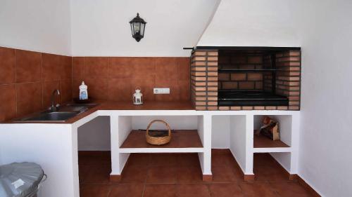 une cuisine avec évier et comptoir avec cheminée dans l'établissement Cortijo Antonio, à Nerja