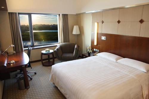 a hotel room with a bed and a desk and a window at Shangri-La Harbin in Harbin