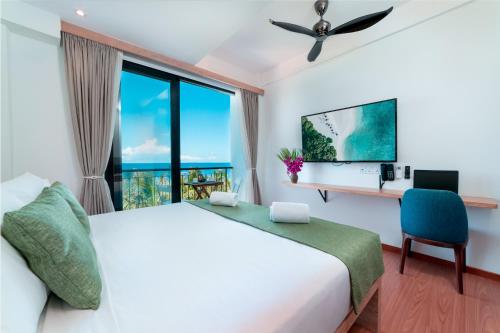 a bedroom with a bed and a desk and a window at Ranthari Hotel and Spa Ukulhas Maldives in Ukulhas