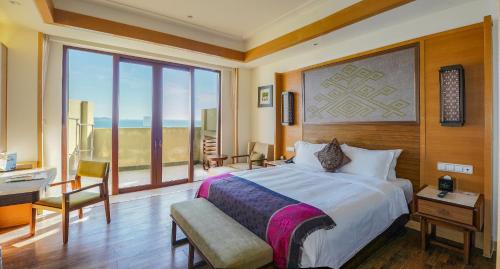 Schlafzimmer mit einem Bett, einem Schreibtisch und einem Fenster in der Unterkunft HNTI·Narada Sanya Bay Resort in Sanya