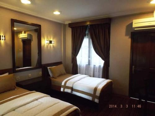 una camera d'albergo con due letti e una finestra di Hotel Bahtera PT.Pelni a Bogor