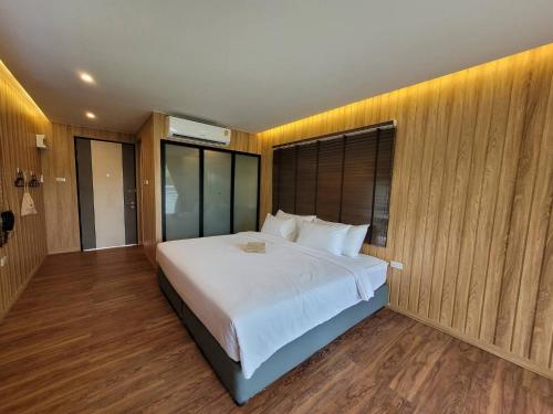 Schlafzimmer mit einem großen weißen Bett und Holzwänden in der Unterkunft Sunnyvale Ranong 2 in Ranong