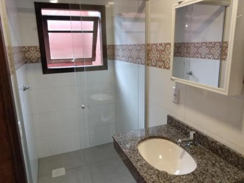uma casa de banho com um lavatório e um chuveiro em Condominio Aldeia da Praia em Garopaba