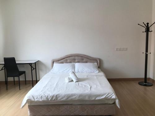 a bedroom with a bed with white sheets and a desk at Island Hostel Bayan Lepas Airport in Bayan Lepas