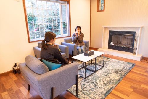 two women sitting in a living room with a fireplace at 青庭 in Ito