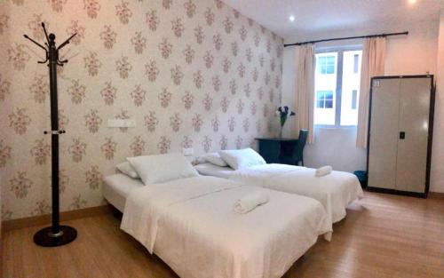 two beds in a hotel room with a cross on the wall at Island Hostel Bayan Lepas Airport in Bayan Lepas