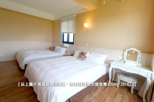two beds in a hotel room with white sheets at Zen Ocean in Jian