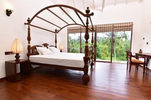 a bedroom with a canopy bed and a desk at Iain Lake Winds Villa in Galle