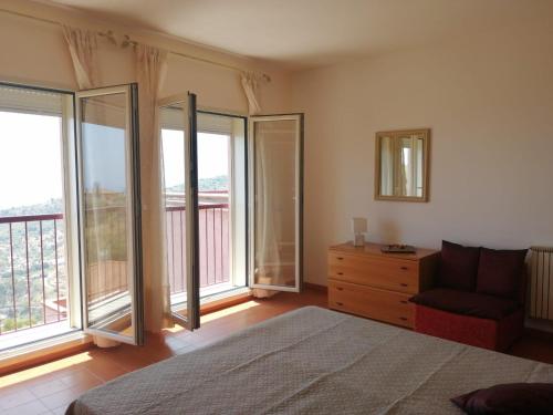 a bedroom with a bed and a chair and windows at Casa Romeo in Taormina