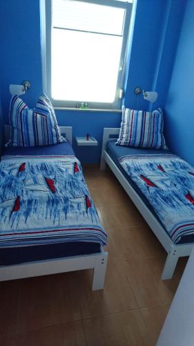 a blue room with two beds and a window at Die kleine Kajüte in Ueckeritz